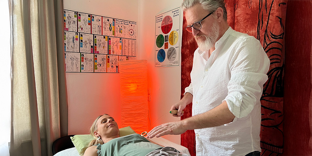 Energetiker Thomas Leitner arbeitet mit dem Tensor am Herzchakra einer Klientin